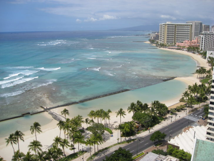 a beach with palm trees and a body of water with Isla Verde, Puerto Rico in the background