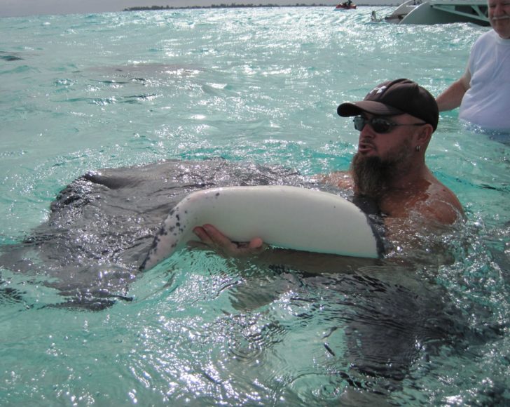 a man holding a stingray in the water