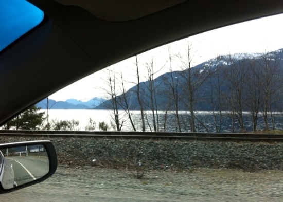 a view of a mountain and lake from a car window
