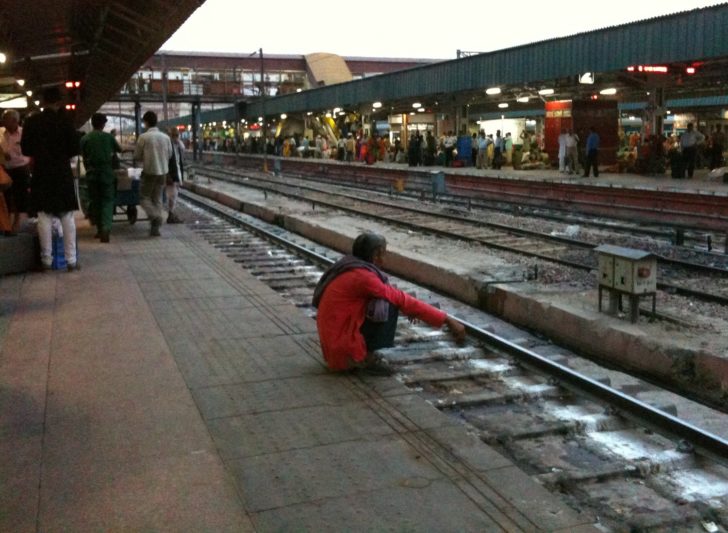 a man kneeling on the ground next to a train track