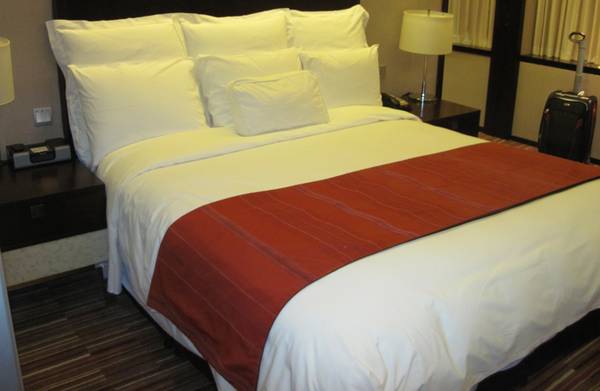 a bed with white sheets and a red runner