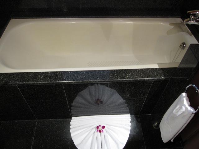 a bathtub with a white towel on the floor