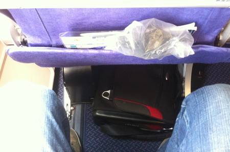 a person's legs and a bag on the side of a seat