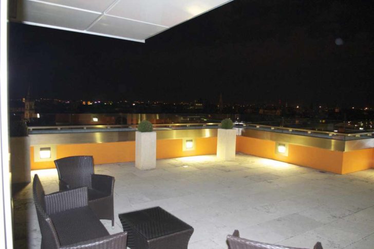 a patio with chairs and a view of the city from the roof