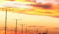 a group of telephone poles with lights at sunset