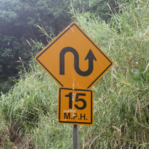 a yellow road sign with a curved arrow