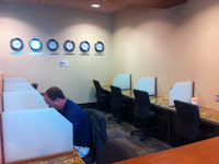 a man sitting at a desk in a room with chairs and a table with clocks