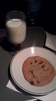 a cookie on a plate next to a glass of milk