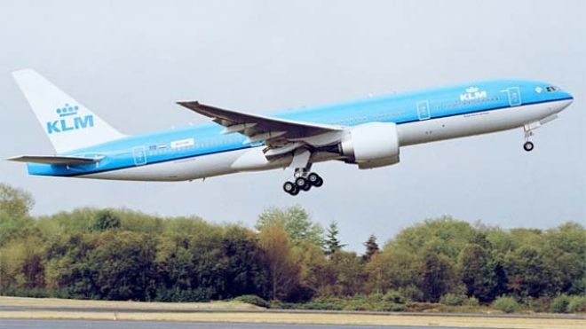 a blue and white airplane flying over a runway