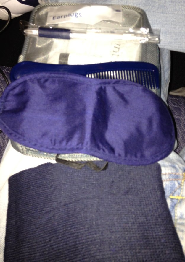a blue eye mask and comb on a blue bag