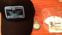 a black cap and keychain with a blue badge