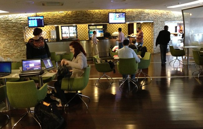people sitting in a room with green chairs and laptops