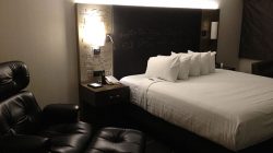 a bed with pillows and a chair in a hotel room