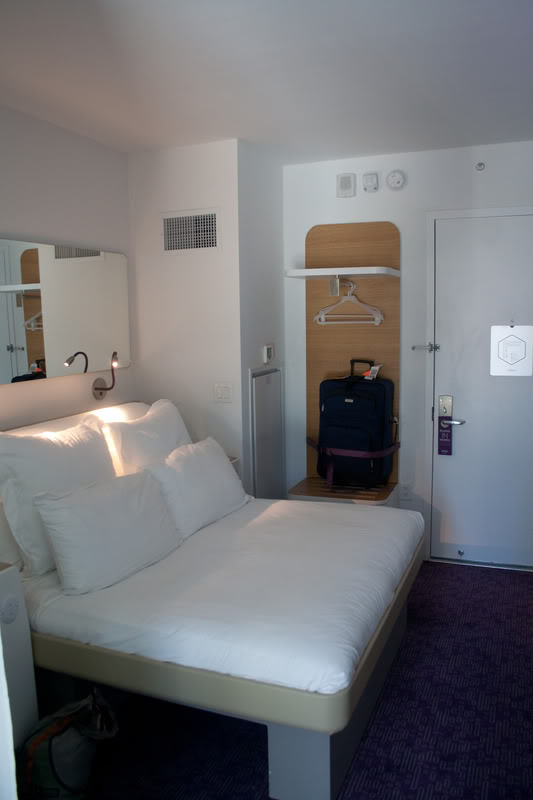 a hotel room with a bed and a suitcase