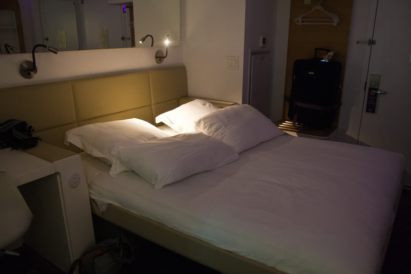 a bed with pillows and a suitcase in the background