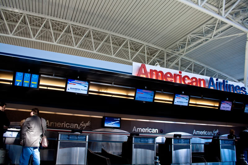 a woman standing in front of an airport check-in counter