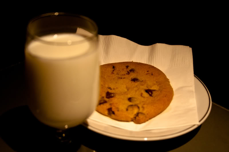 a cookie on a plate next to a glass of milk