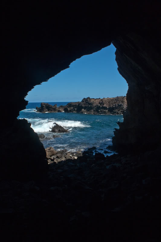 a cave with rocks and water in the background