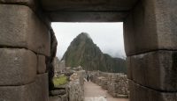 stone archway with stone walls and a mountain in the background