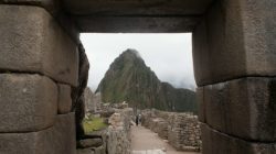 stone archway with stone walls and a mountain in the background