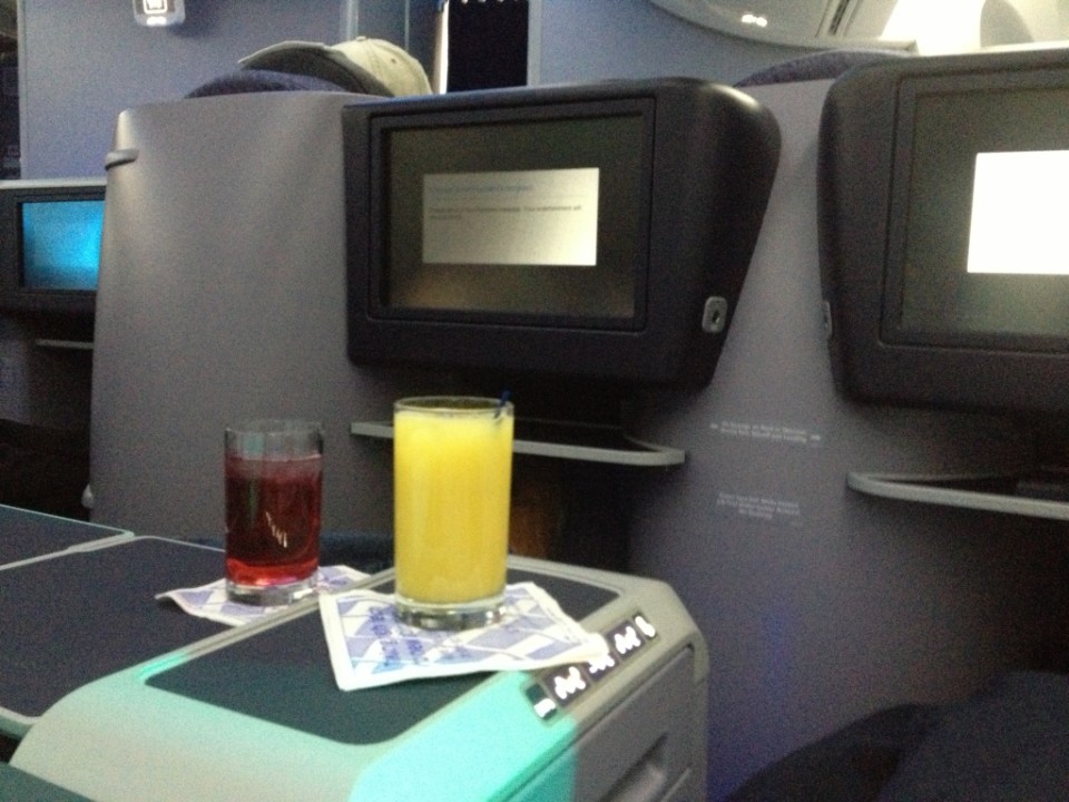 a glass of juice and a drink on a table in an airplane