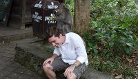 a man sitting on a stone ledge with a monkey on his head