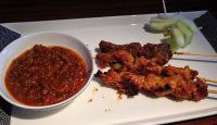 a plate of food with a bowl of sauce and sticks