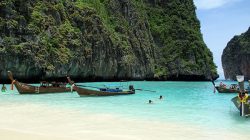 boats in the water near a cliff with Phi Phi Islands in the background