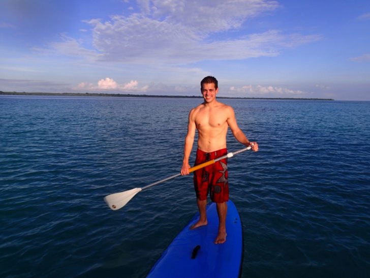 a man standing on a surfboard with a paddle