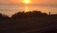 a road with a sunset over the water