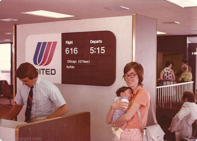 a woman holding a baby in front of a sign