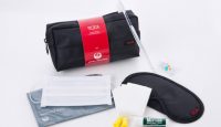 a black bag with a red label next to a black mask and a toothbrush