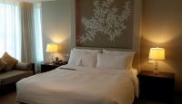 a bed with a lamp and a painting on the wall