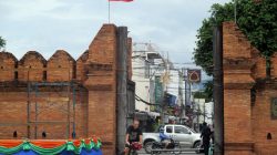 a man riding a bicycle in front of a brick wall