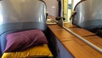 a bed with a purple pillow and yellow pillow on a wooden table