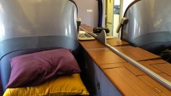a bed with a purple pillow and yellow pillow on a wooden table