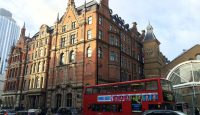 a double decker bus and cars in front of a large building