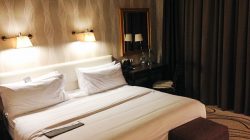 a bed with white sheets and a mirror in a hotel room