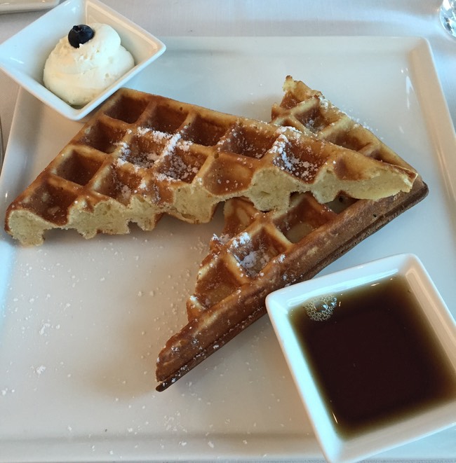 waffles on a plate with syrup and a blueberry on top