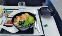 a bowl of soup with vegetables and a fork on a tray