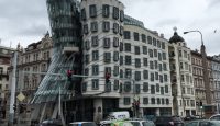 Dancing House with a curved roof and many cars on a street