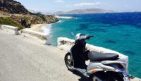a scooter parked on a road next to a body of water