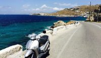 a scooter parked on a road next to a body of water
