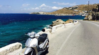 a scooter parked on a road next to a body of water