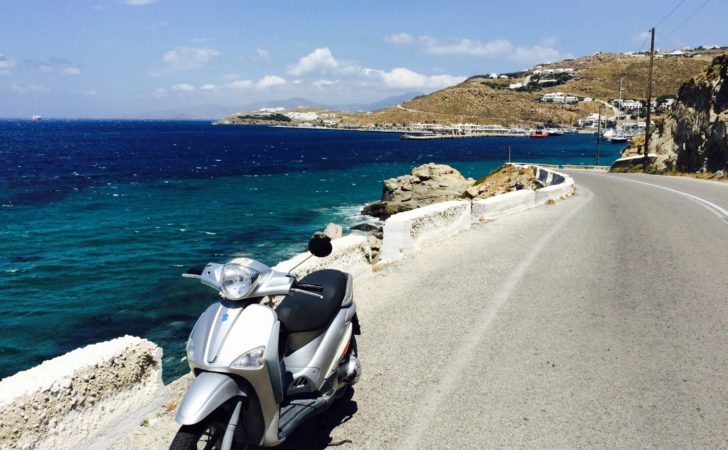 a scooter parked on a road next to a body of water