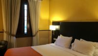 a bed with white pillows and a lamp in a room with yellow walls