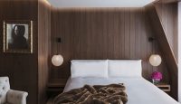 a bed with a brown blanket and lamps in a room