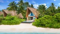 a house on a beach with palm trees