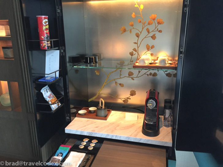 a glass shelf with cups and coffee maker on a marble counter