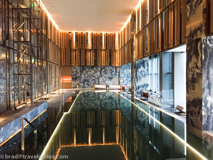 a indoor pool with a marble wall and glass walls